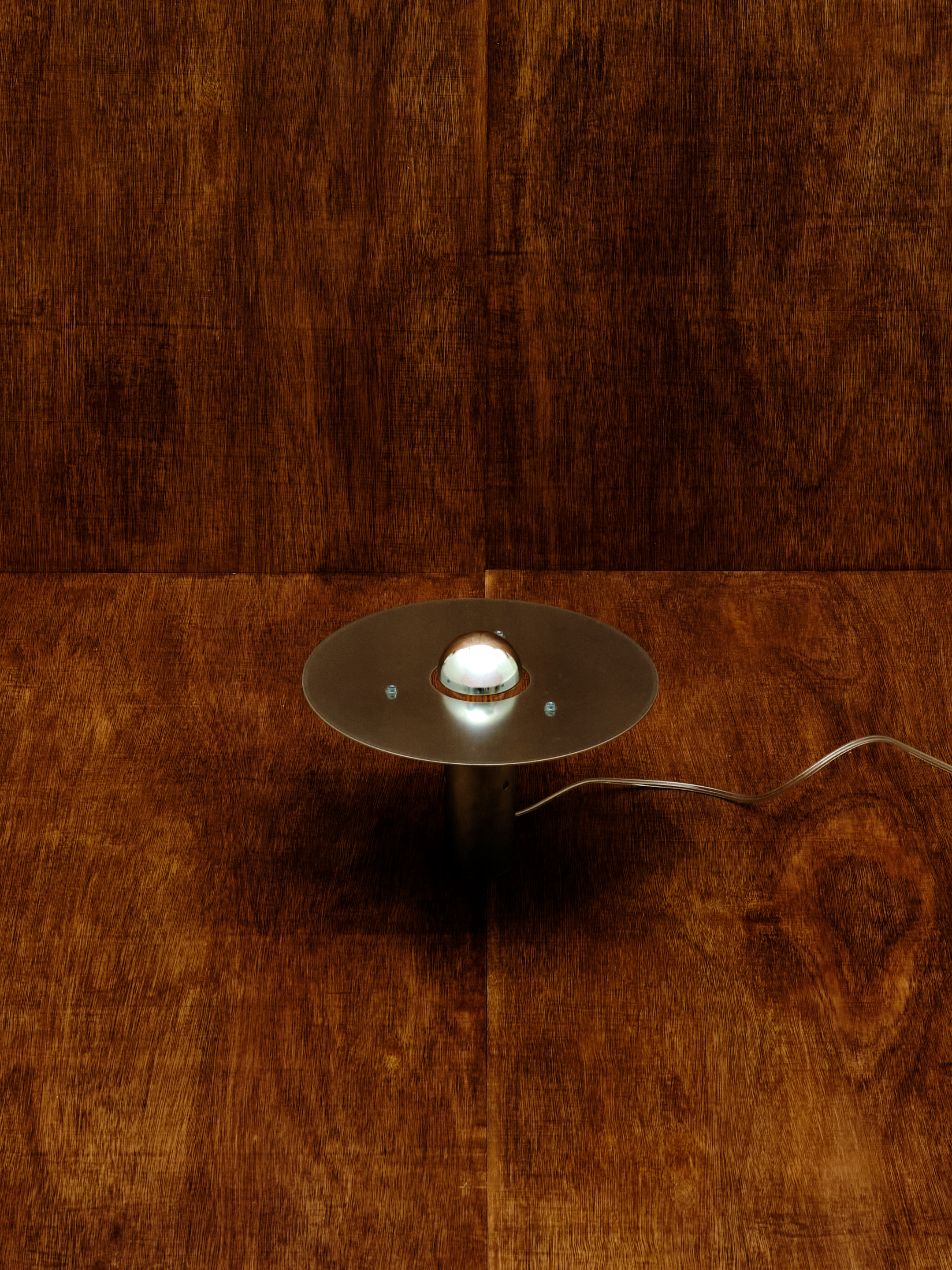 Small round lamp with a reflective surface on a wooden floor