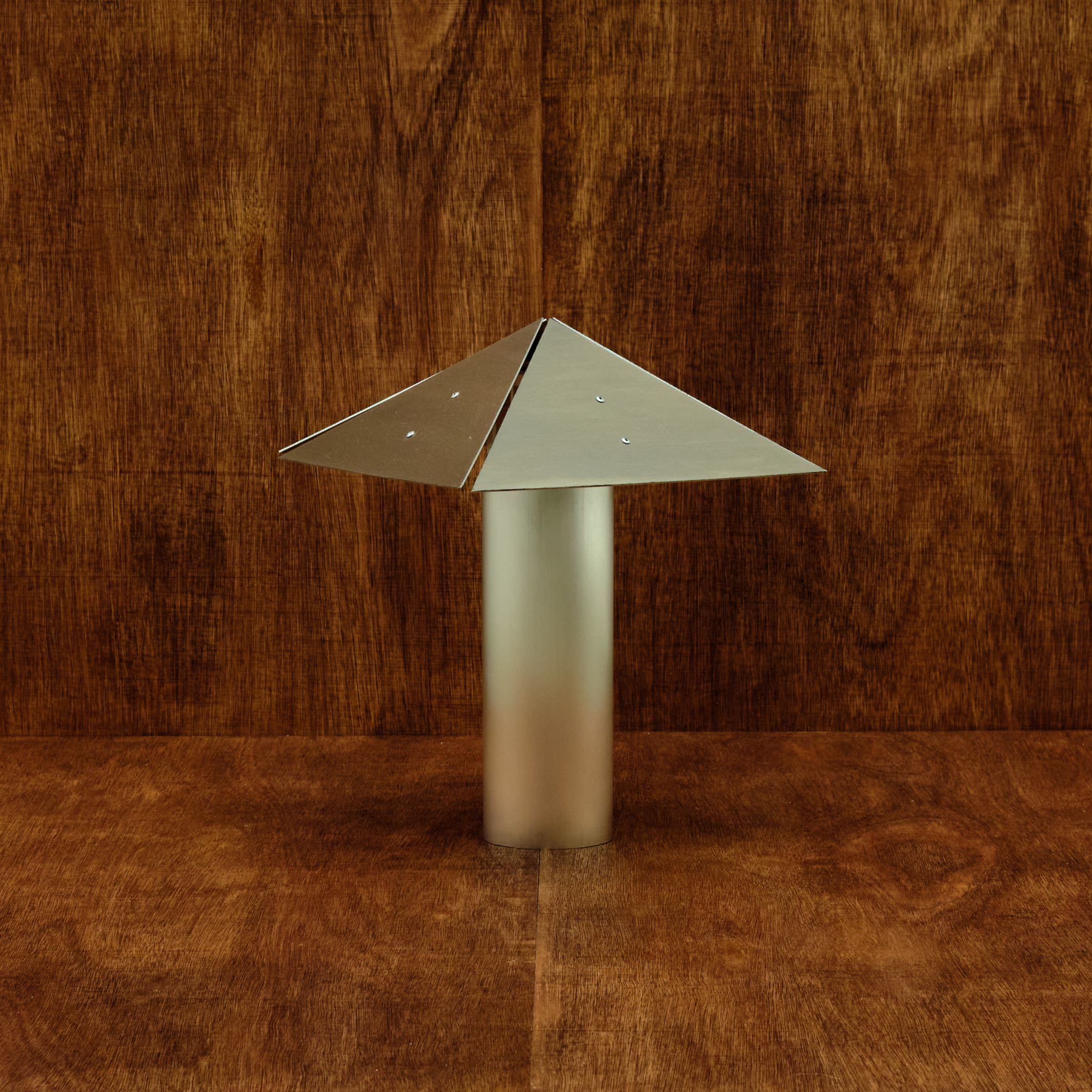 Metallic lamp with a triangular shade on a wooden background