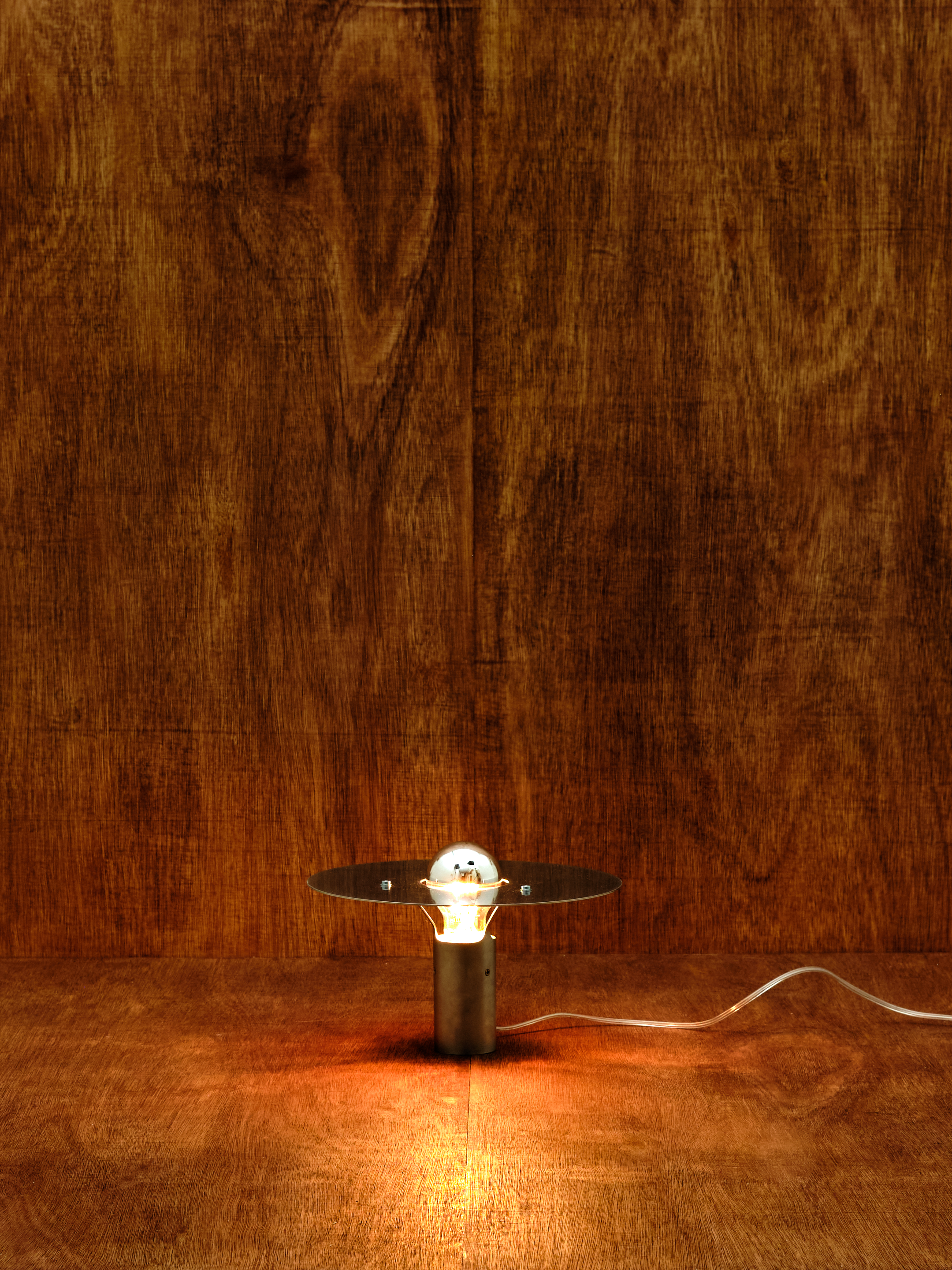 Small table lamp with a lit bulb on a wooden surface
